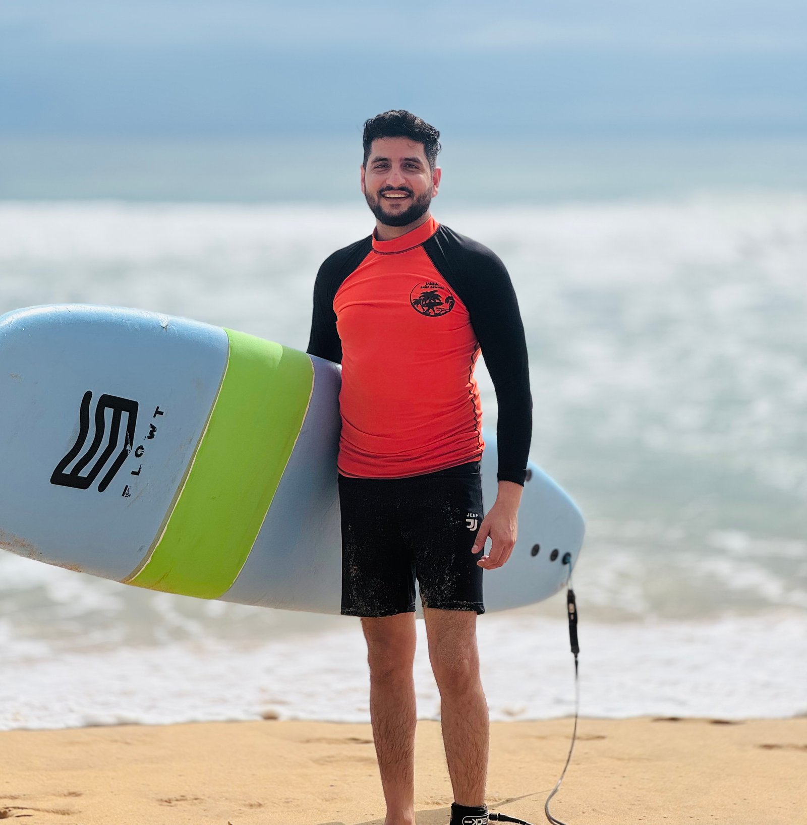 Mayank, founder and host of OPEN ENDS, at the beach with a surfboard